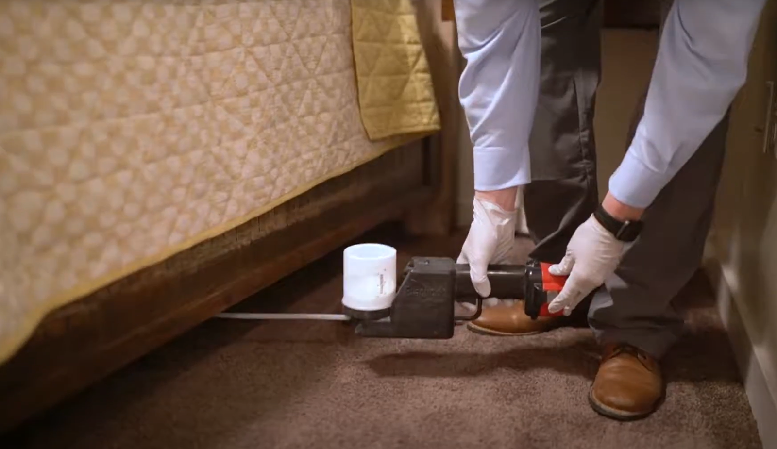 Pest control specialist inspecting and treating under a bed with tools during a Pest Control Service in Englewood visit.